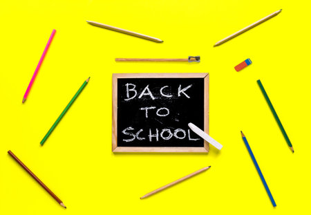 Back to school concept, chalkboard with pencils on yellow background
