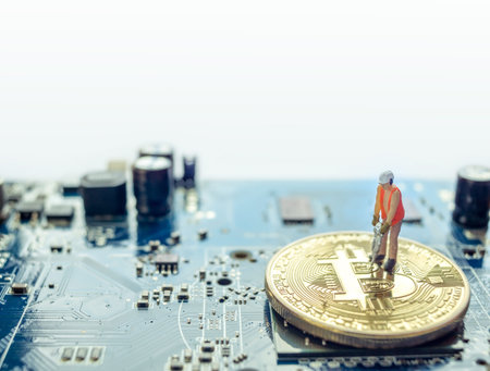 Miniature construction worker standing on physical Bitcoin, isolated mining concept