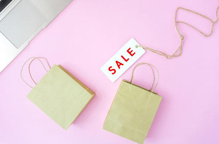 Sale tag with small shopping bags on pink background, online shopping conceptの写真素材