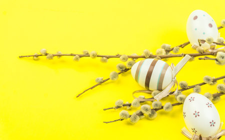 Easter yellow background with eggs hanging on branches of pussy willow.