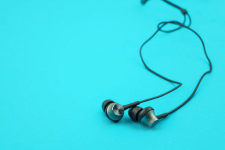 Metal ear buds and wires on blue background, low angle with copy spaceの写真素材