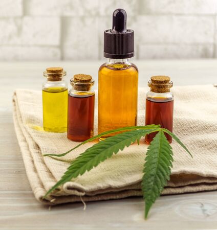Various Cannabis CBD Full spectrum and THC oils and Hemp cloth on wooden backdropの写真素材