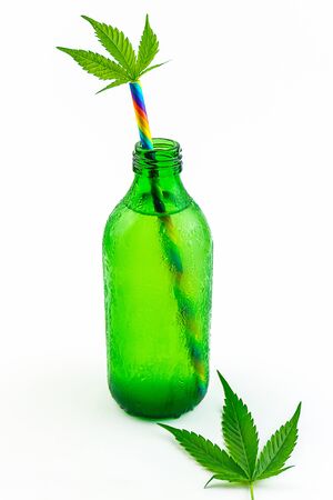 Green glass bottle with Cannabis CBD infused Water lemonade with cannabis leafs isolated on whiteの写真素材