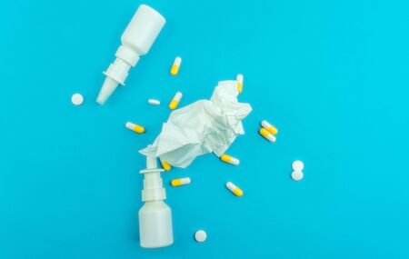 Pills, nasal spray and wrinkled tissue against blue background, cold or allergies conceptの写真素材