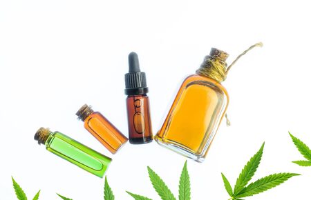 Glass bottles with CBD oil and THC tincture and hemp leaves on white background. Flat lay Cosmetics cannabis oil.の写真素材