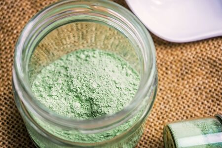 Mitragyna speciosa or Kratom powder in ceramic spoon and glass jars on table with hemp clothの写真素材
