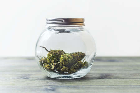 Medical Marijuana in glass jar on table against white backgroundの写真素材