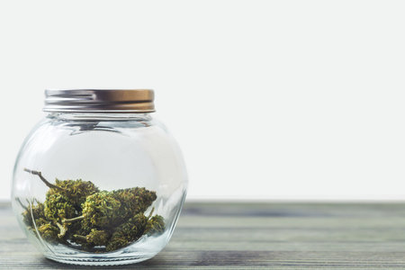 Medical Marijuana in glass jar on table against white backgroundの写真素材