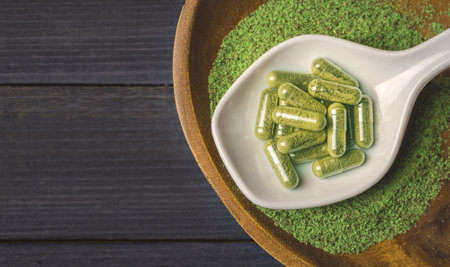 Coarse grind Mitragynina speciosa or Kratom powder and Kratom pills on grayの写真素材