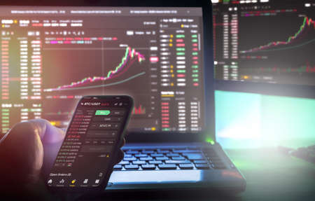 Vienna Austria January 27th 2021, Daytrader working from home using Binance app on Computer screen and phone with chartsのeditorial素材