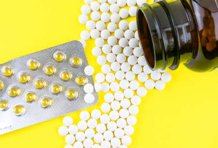 Many gel capsules of vitamin D3 2000 IU and Vitamin K2 pills on yellow backgroundの写真素材