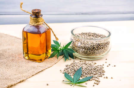 Cannabis seeds in glass bowl on table and hemp cloth with oil rich in protein and healthy fatsの写真素材