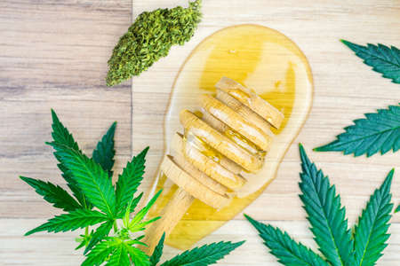 CBD Cannabis infused Honey with dipper spoon jar Marijuana leafs on wooden table, Cannabis products in food industryの写真素材