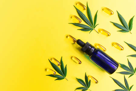 CBD Cannabidiol bottle Capsules and Cannabis leafs on yellow background, alternative medicine conceptの写真素材