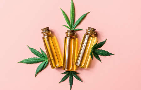 CBD Cannabidiol oil bottle and Cannabis leafs on pink backgroundの写真素材