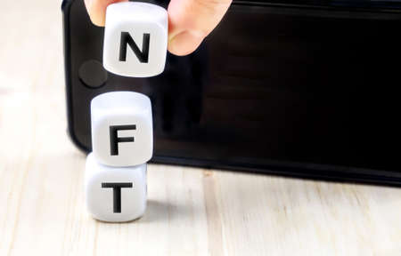 NFT or Non-Fungible token letters and dices, nft's are a blockchain market for art and collections smart phone with copy spaceの写真素材