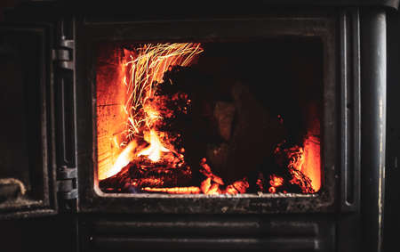Fire burning glowing in rustic wood burning cast iron stove, log burner for heating or fireplaceの写真素材