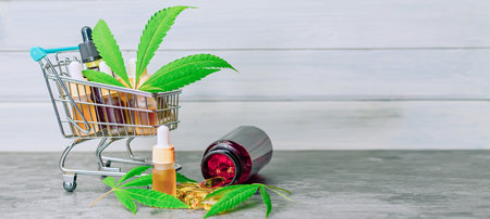 Supermarket trolley basket with cannabis Cbd or THC oils capsules, CBD purchasing concept with copy spaceの写真素材