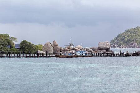 Tropical sea islands top view landscape. Small tropical island with white sandy beach. Beautiful island on the atoll, view from above. Tropical sea island beach view. Island sea beach scene. The ship is at the pier.の写真素材