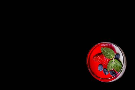 Place the text next to a glass of homemade yogurt. Homemade yogurt with red berry jelly or yogurt in glasses is served with fresh strawberries, honeysuckle and mint leaves. Close up. Dark background.の写真素材
