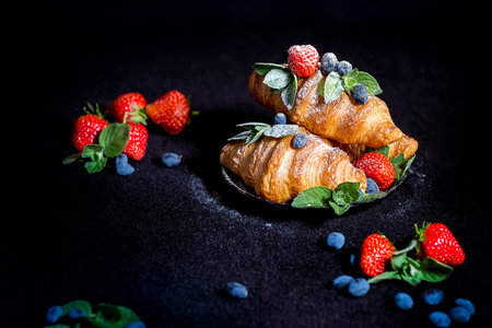 Croissants on a dark background. Croissant with berries. French Breakfast with croissants....