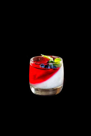 Homemade yogurt with red berry jelly or yogurt in glasses is served with fresh strawberries, honeysuckle and mint leaves. Close up. Dark background.の写真素材