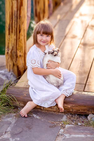 Portrait of a girl with a rabbit. A girl holds a pet rabbit in her hands. Nature walk. Close up.の写真素材