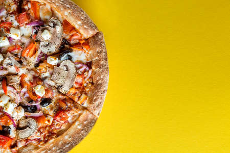 Half A pizza with vegetables is on a bright yellow background. Space for text. The view from the top.の写真素材