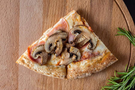 A slice Of pizza with mushrooms lies on a wooden cutting Board on a dark background.Four different pizza flavors. Space for text. The view from the top.の写真素材