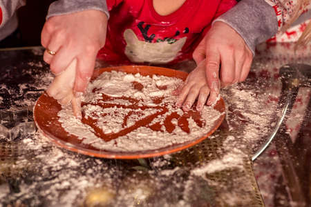 A girl with her mother cut cookies from raw dough-a Christmas treat for Santa Claus. Hands close-up. selective focus. homemade cakes, Christmas sweets, the concept of a winter holiday.の写真素材