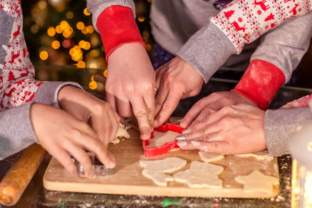 Children cut out cookies from raw dough with a cookie cutter. Christmas treat for Santa Claus. Hands close-up. Selective focus. Homemade cakes, Christmas sweets, the concept of winter holidays.の写真素材