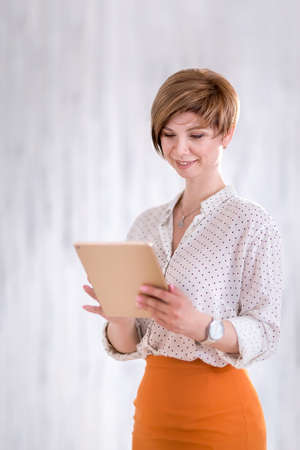 Portrait of a happy woman standing with a Notepad and pen. A business woman thinks through and writes her work plan. Successful small business owner in business attire.の写真素材