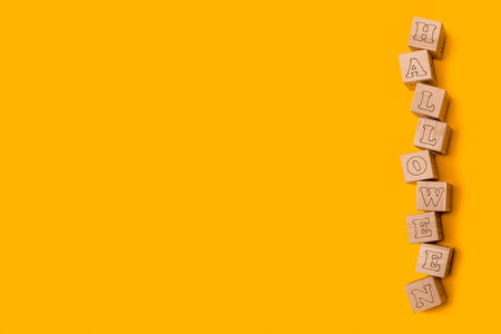 background design in the style of Halloween, letters on wooden cubes. Solid orange background. Flat...