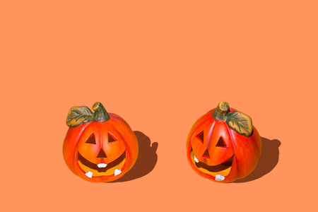 Halloween style background design, two Jack heads carved pumpkins on the background. Solid orange...