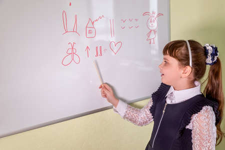 A girl pupil stand at the blackboard and tells a story from drawingsの写真素材