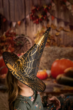 Portrait of a girl in a witch costume, preparing for Halloween. Puts on a medical face mask that...