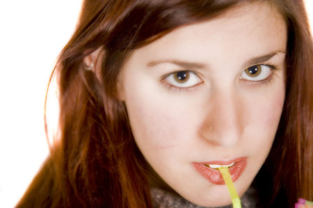 a pretty girl with a straw in her mouyh looking at the cameraの写真素材