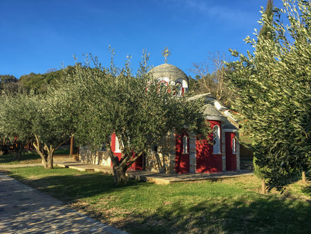 A small church on Mount Athos with red walls, tiled with a baptistery and a bell