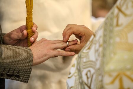 The priest puts a wedding ring on the grooms finger.の写真素材