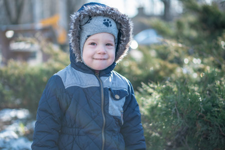 A child playing hide and seek behind juniper bushes in winter