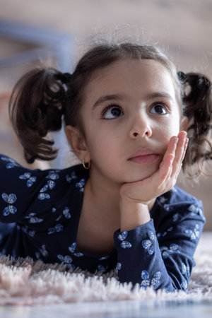 Middle Eastern young cute girl lies on a light bed in the light of sunlight. Persian swarthy girl on...