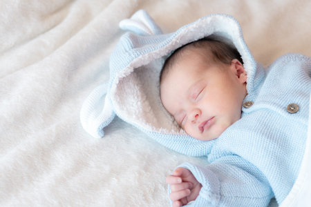 Newborn baby close-up, place for text. Newborn sleeping on his back in a blue blouse on a white...