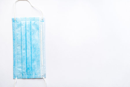 Medical blue disposable protective mask on a white background copy space. A surgical dressing closes...