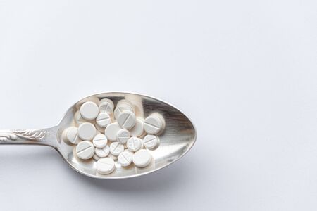 Medicine and health, treatment, pharmacy, coronavirus, pandemic, epidemic concept - layout one silver big tablespoon with different pills and capsules on a white background copy space.の写真素材