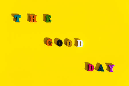 layout of wood multicolored letters is inscription of good day with shadows on bright plain yellow background. wishes and messages made up of models of alphabet: gifts, postcards, screensavers concept.の写真素材