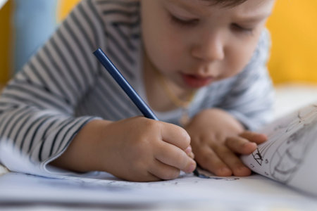 smart smiling preshool toddler children boy and girl draw with pencils lying on their stomach at...