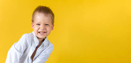 Banner Funny Preschool Child Boy in unbuttoned shirt smile narrow eye on Yellow Background Copy Space. Happy Smiling Kid Go Back to School, Kindergarten. Success, Motivation, Genius, Superhero conceptの写真素材