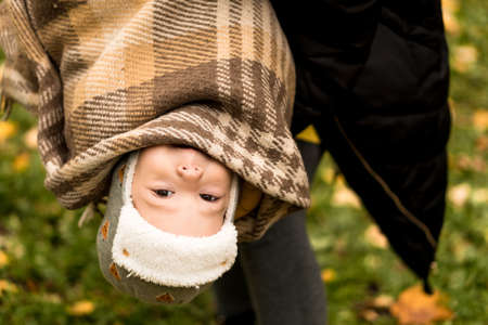 Young Woman Mom Holding Little Baby Boy Son Upside Down In Orange Plaid At Yellow Fallen Leaves Nice Smiling Look At Camera In Cold Weather In Fall Park. Childhood, Family, Motherhood, Autumn Conceptの写真素材
