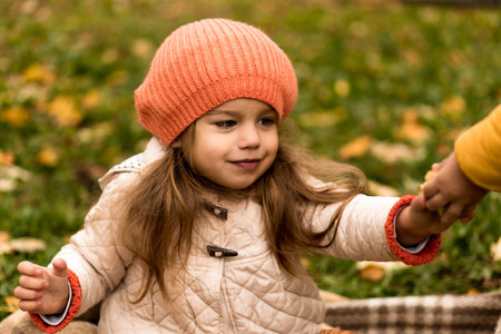 Portrait Of Little Cute Preschool Minor Girl In Orange Beret On Yellow Fallen Leaves Takes Apple...