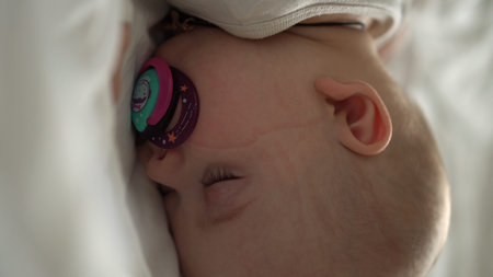 Vertical close-up face newborn chubby sleeping baby lying on stomach open eyes and smile covered...